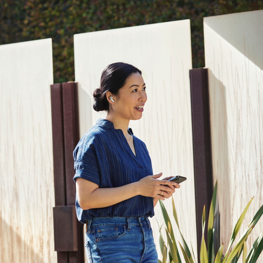 A person walking outdoors stays connected on-the-go via Webex on her mobile phone.